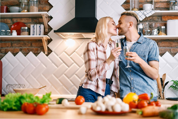 Young happy couple drinking champagne and enjoying the company of each other in kitchen at home - Foto, Imagem