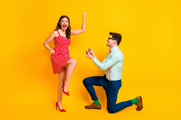 Full body photo of tow people nerd style man propose girl ecstatic raise fists wear red dotted dress high heels legs mini short suspenders pants isolated over bright shine color background - 写真・画像