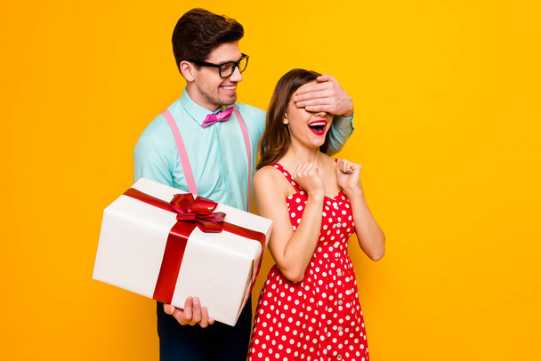 Photo of pretty lady handsome guy couple boyfriend giving girlfriend big gift box close eyes guess who game wear red dress shirt bowtie pants isolated yellow bright color background - Photo, image