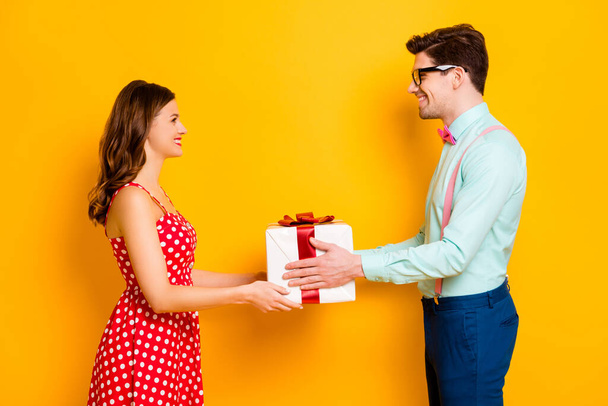 Profile photo of pretty lady handsome guy couple boyfriend giving girlfriend big gift box 8 march present wear red dotted dress shirt bowtie pants isolated yellow bright color background - Zdjęcie, obraz