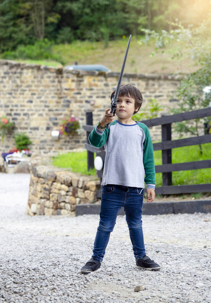 Aktivní chlapec hrající si venku s mečem, Portrét dítě hrající si s hračkou na zahradě za slunečného dne v létě, Dítě držící plastový meč, Aktivity venku pro děti koncept - Fotografie, Obrázek