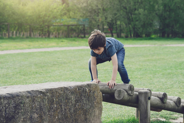 Actief kind spelen evenwicht op houten balk in park, Kleine jongen klimmen op een houten speelplaats, Happy Child veel plezier spelen buiten in het park in de zomer. - Foto, afbeelding