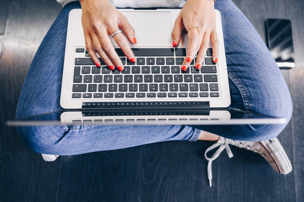 Femme travaillant sur un ordinateur portable assis sur le plancher. - Photo, image