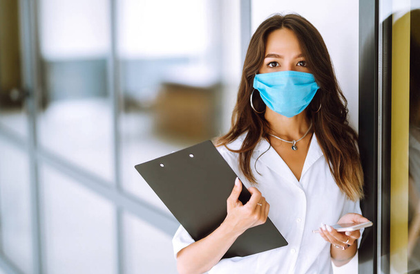 Office worker with face mask working in the office. The concept of preventing the spread of the epidemic and treating coronavirus, pandemic in quarantine city. Covid-19. - Foto, imagen