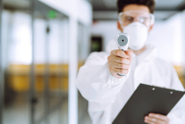 Disease control expert with an Infrared thermometer equipment to check the temperature. The concept of preventing the spread of the epidemic and treating coronavirus, pandemic in quarantine city.  - 写真・画像