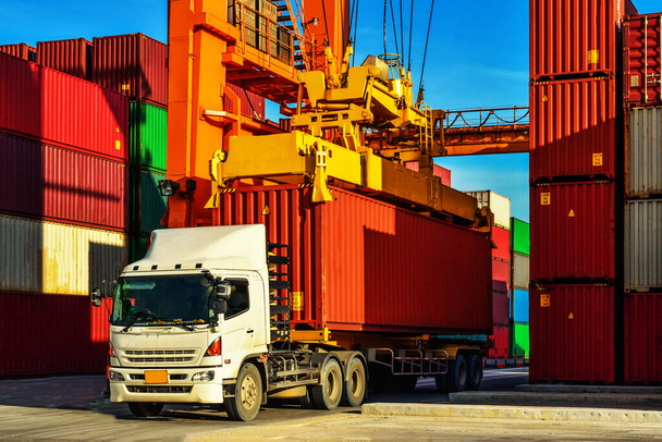 Containerumschlag. Container-LKW nimmt Container auf dem Hof auf. Hafenlogistik, Containerwerftbetrieb. - Foto, Bild