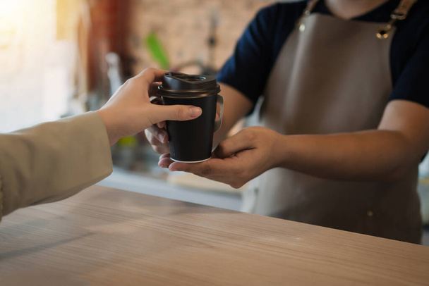 young happy handsome man barista serving hot coffee cup to friendly female customer over counter in modern cafe coffee shop, cafe restaurant, service mind, small business owner food and drink concept - Fotoğraf, Görsel