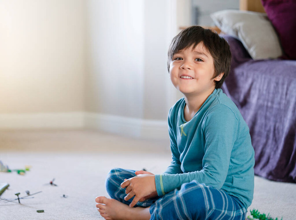 Щасливий хлопчик сидить на килимовій підлозі, грає з солдатами та фігурними іграшками в житловій кімнаті, Вибірковий фокус Дитина грає війни та спокій самостійно вдома, Дитяча уява та розвиток
  - Фото, зображення