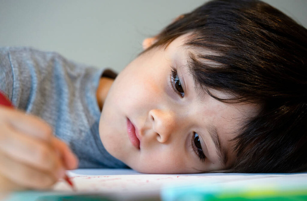 Αυτοσυγκέντρωση μοναχικό παιδί αγόρι ξαπλωμένο στο τραπέζι με λυπημένο πρόσωπο, συναισθηματικό πορτραίτο πεντάχρονου παιδιού βαριέται με σχολική εργασία, κακομαθημένο παιδί - Φωτογραφία, εικόνα