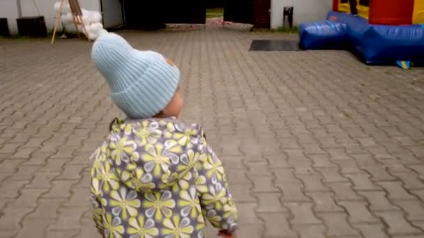 Nimetön lapsi kävelee kohti pomppulinnaa - Materiaali, video
