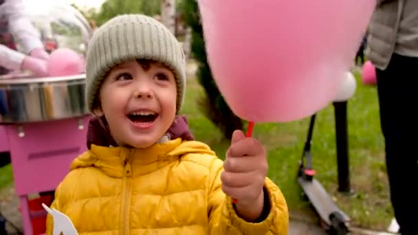 Chłopiec je nici cukierkowe w parku - Materiał filmowy, wideo