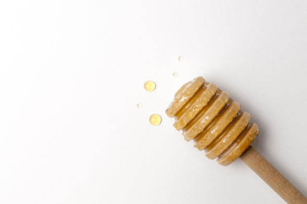 Honey dipper with some honey drops on white background - Foto, immagini