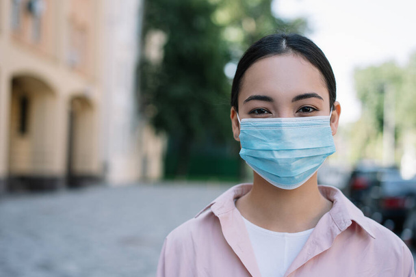 Portrait of pensive asian doctor wearing medical mask to protect from coronavirus infection looking at camera. Quarantine, virus, concept - Foto, imagen