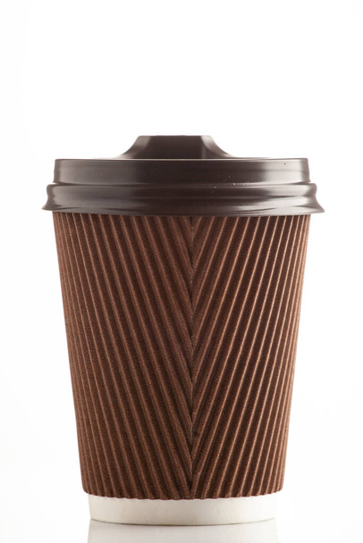 Papel marrón taza ondulada sobre un fondo blanco con una tapa. Un vaso para bebidas calientes. Bebidas para llevar
. - Foto, imagen