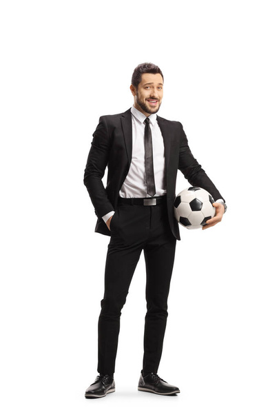 Teljes hosszúságú portré egy fekete öltönyös férfiról, aki egy fehér alapon elszigetelt focilabdát tart. - Fotó, kép