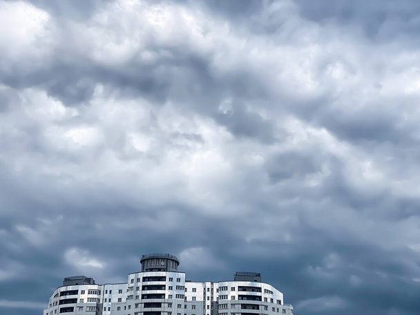 Θολωμένος ουρανός με σύννεφα πριν την καταιγίδα. Σύγχρονος ουρανοξύστης ενάντια στον θυελλώδη ουρανό. Πλησιάζει καταιγίδα.. - Φωτογραφία, εικόνα