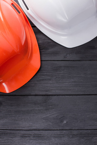 Construction workers helmets on dark wood. - Фото, изображение