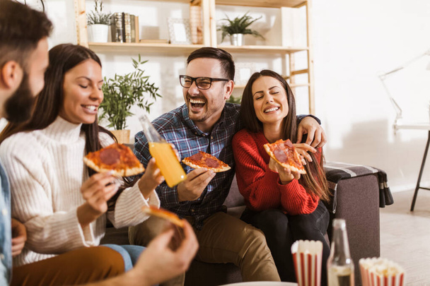 Ryhmä nuoria ystäviä syö pizzaa kotona sisustus. Nuorilla on hauskaa yhdessä.  - Valokuva, kuva
