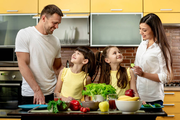 Muotokuva onnellinen perhe, äiti isä ja kaksi tytärtä, ruoanlaitto salaatteja keittiössä kotona. Terveellinen syöminen käsite - Valokuva, kuva