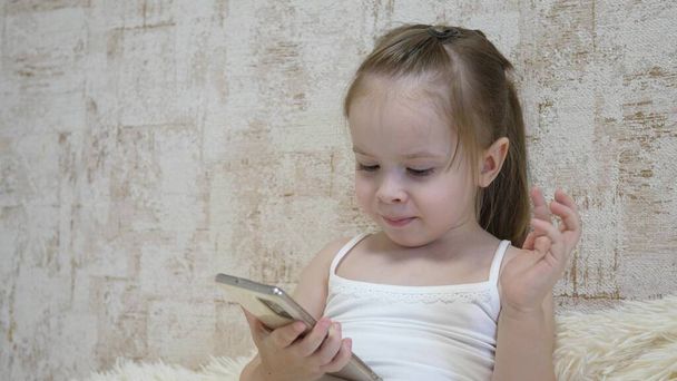 小さな子供がビデオ通話で電話で話している。子供はモバイルアプリケーションを介してリモートで通信します。インターネットを使った就学前教育。閉鎖 - 写真・画像