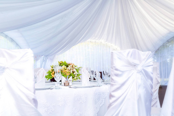 Esküvő egyszerű szabadtéri asztal beállítás egy fehér szabadtéri sátorban. - Fotó, kép