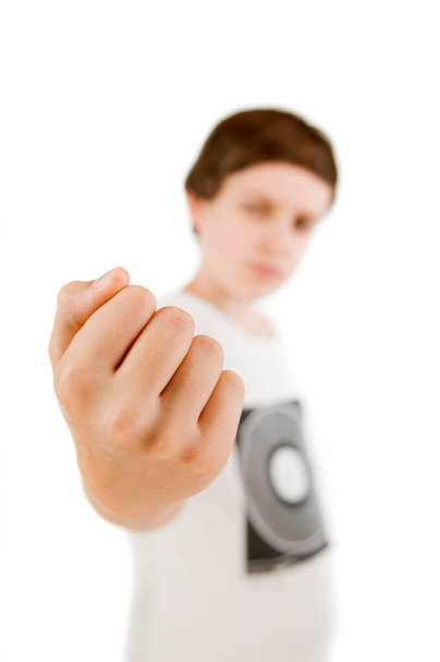 Blurred upper body view of a young male Caucasian teenage boy against white background stretching his right fist in focus towards the camera. - Photo, Image