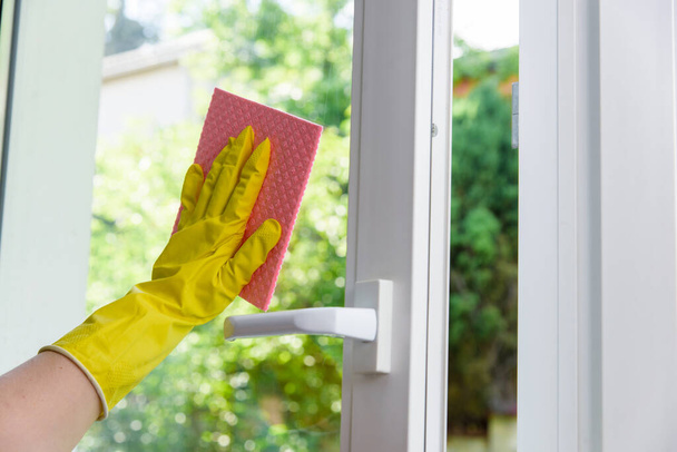 Cleaning of opened vinyl window. Protective glove on hand and cleaning cloth - Fotoğraf, Görsel