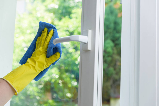 Cleaning of opened vinyl window. Protective glove on hand and cleaning cloth - Photo, Image