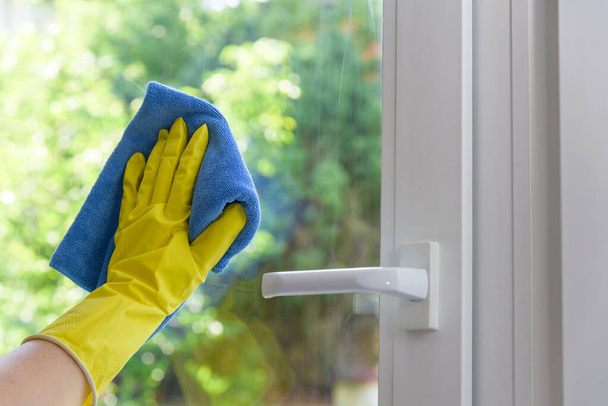 Cleaning of closed vinyl window. Protective glove on hand and cleaning cloth - Foto, Bild