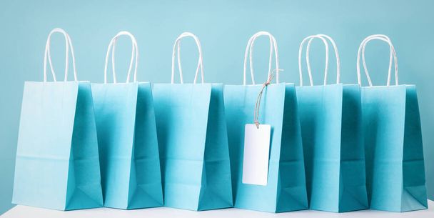 koncepcja zakupów. Niebieskie papierowe torby na zakupy stojące w kolejce na stole - Zdjęcie, obraz