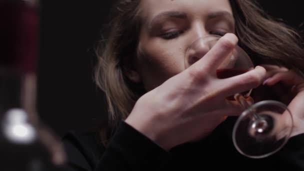 Young beautiful woman in severe depression, drinking alcohol. The concept of abuse and alcoholism. Alcoholic woman with bottle and glass of wine.  - Video