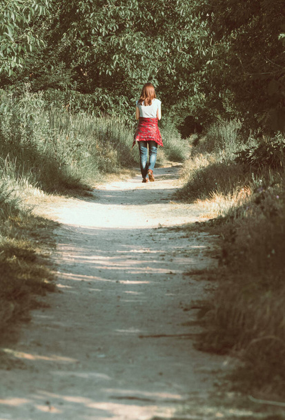 Magányos vörös hajú lány sétál a természet ösvényén. Vintage megjelenés. - Fotó, kép