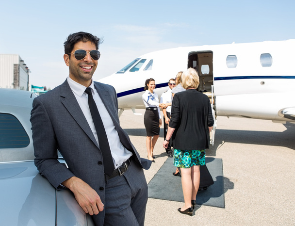 Happy Businessman Leaning On Car At Airport Terminal - Foto, imagen
