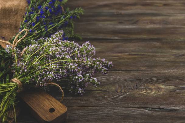 Bunches of medicinal herbs with purple and blue flowers copy space. Thyme and hyssop flowers on a wooden table. - Photo, Image