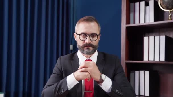 Video portrét Přiblížit, vousatý vůdce nosí brýle a oblek sedí v kanceláři. - Záběry, video