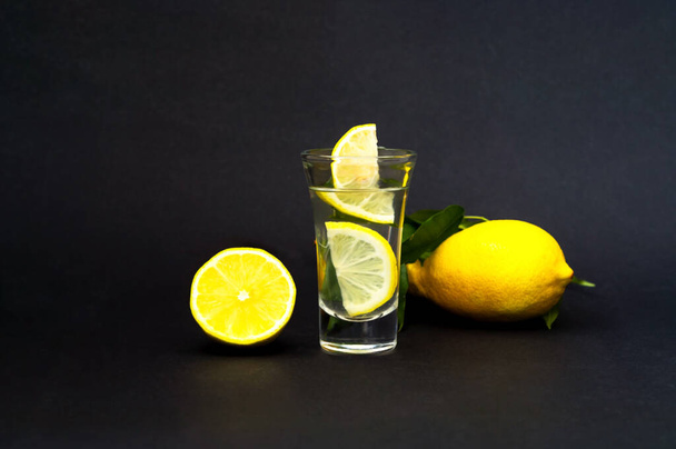 クアドランティニまたは自家製テキーラ。暗い背景にレモンとアルコール飲料covid 。新しい人気ドリンクのコンセプト。閉鎖、コピースペース. - 写真・画像