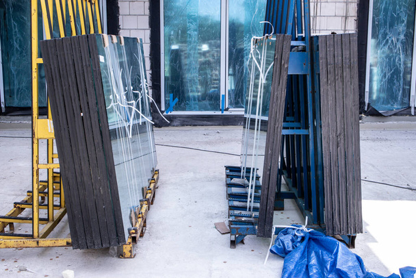 Soporte con grandes paneles de vidrio en el sitio de construcción
 - Foto, Imagen