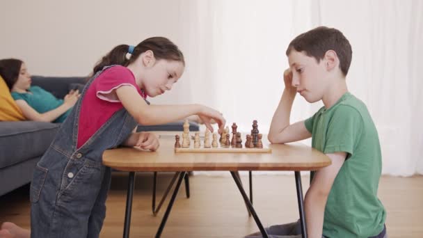 Young kids playing Chess on the living room table - Filmati, video