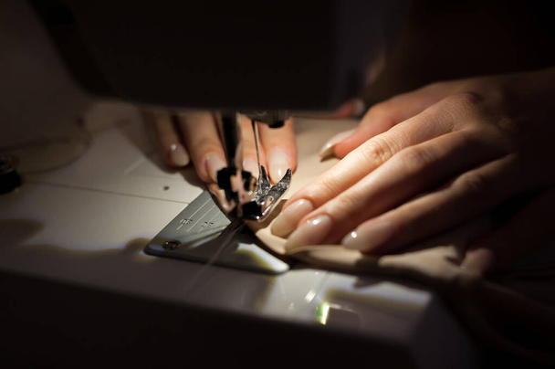 A mulher está costurando com máquina de costura. Costura é o ofício de fixação ou fixação de objetos usando pontos feitos com uma agulha e linha. Costura é uma das mais antigas das artes têxteis
. - Foto, Imagem