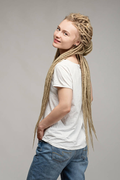 young attractive hippie girl with braided dreadlocks on her head, hands in pockets - Fotó, kép