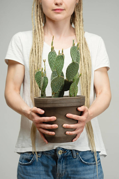 長いドレッドロックの少女はサボテンを手に植物の近くで - 写真・画像