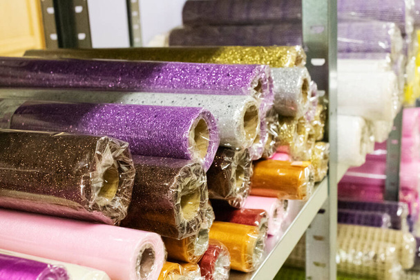 Skladové obalové materiály. Rolls of decorative wrapping paper of different colors are on the store shelf. - Fotografie, Obrázek