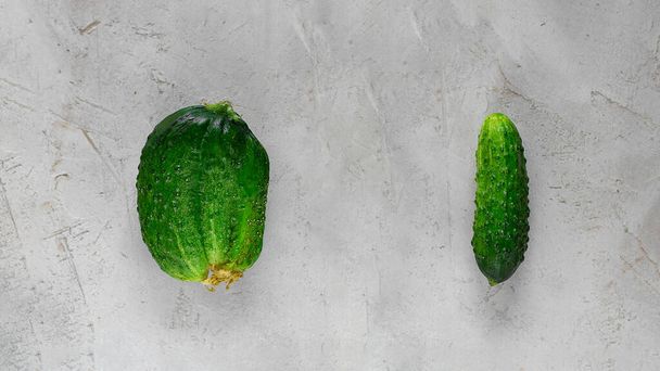 Fresh Ugly triple green organic and normal cucumber on grey cement background with copy space. Food concept of Buying imperfect product to reduce waste. Banner with Vegetable with unusual shape - Foto, Bild