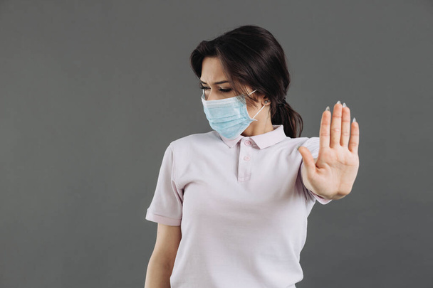 Een vrouw met een medisch beschermend masker toont een coronavirus stop gebaar. - Foto, afbeelding