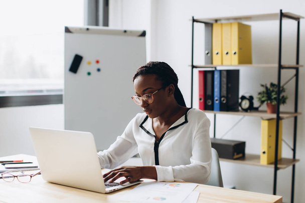 Csinos afro-amerikai üzletasszony dolgozik laptop az irodában - Fotó, kép