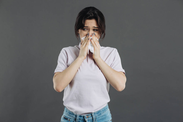 Symptome des Coronavirus. Eine Frau mit Serviette hat eine starke laufende Nase und Husten - Foto, Bild
