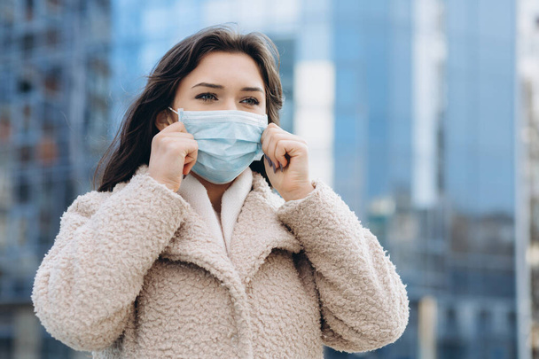 Female wearing medical protective mask outdoors. Health protection prevention during flu virus outbreak, coronavirus COVID-19 epidemic and infectious diseases in the city - Fotó, kép