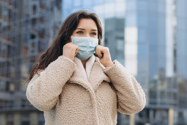 Γυναίκα φοράει ιατρική προστατευτική μάσκα σε εξωτερικούς χώρους. Πρόληψη της προστασίας της υγείας κατά την έξαρση του ιού της γρίπης, επιδημία coronavirus COVID-19 και μολυσματικές ασθένειες στην πόλη - Φωτογραφία, εικόνα
