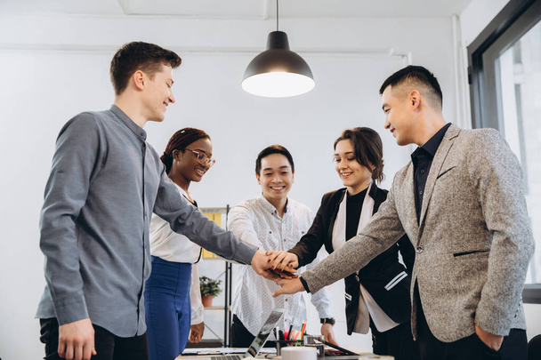 Multiracial euphoric business team people give high five at office table, happy excited diverse work group engaged in teambuilding celebrate corporate success win partnership power teamwork concept - Photo, Image