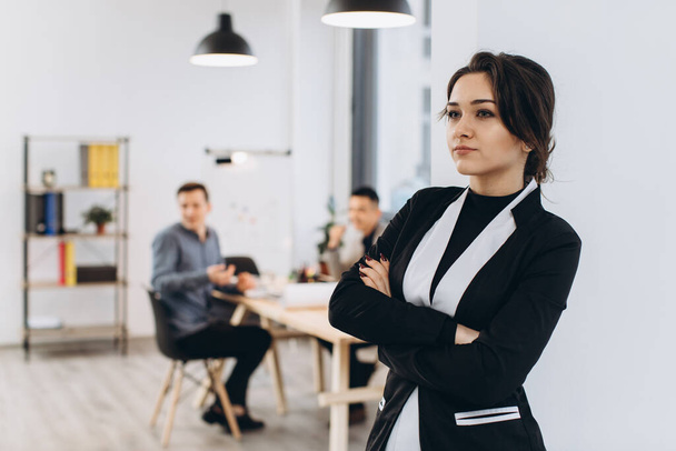 Geschäftsfrau mit ihren Mitarbeitern, Menschen im Hintergrund in modernen, hellen Büroräumen - Foto, Bild